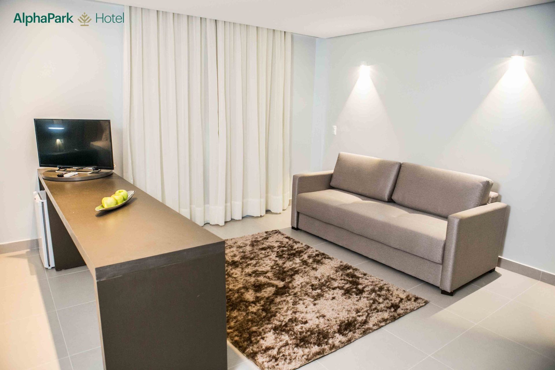 Uma sala de estar com um sofá, escrivaninha e televisão.