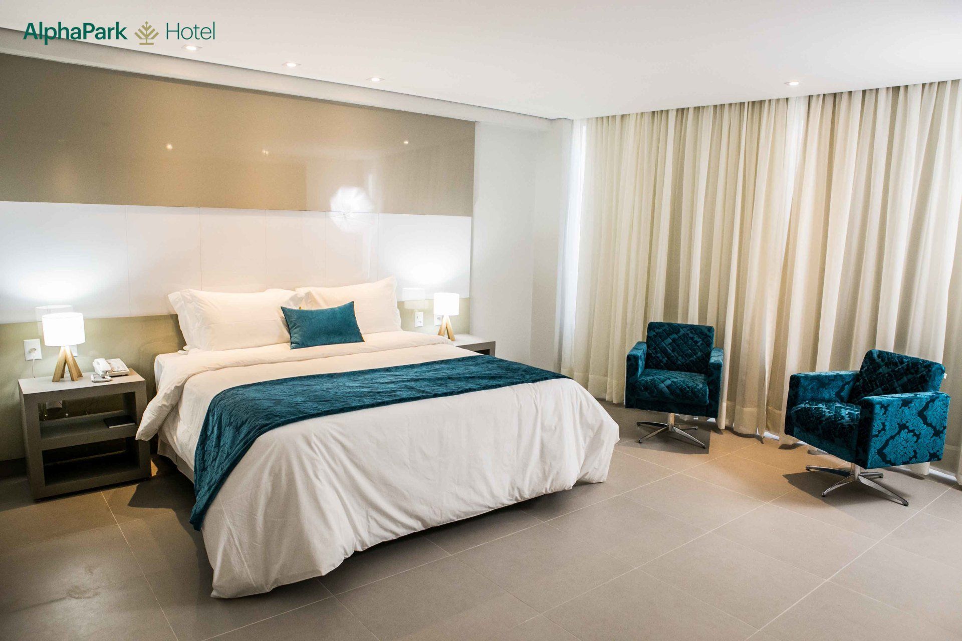 Um quarto de hotel com uma cama grande e duas cadeiras.