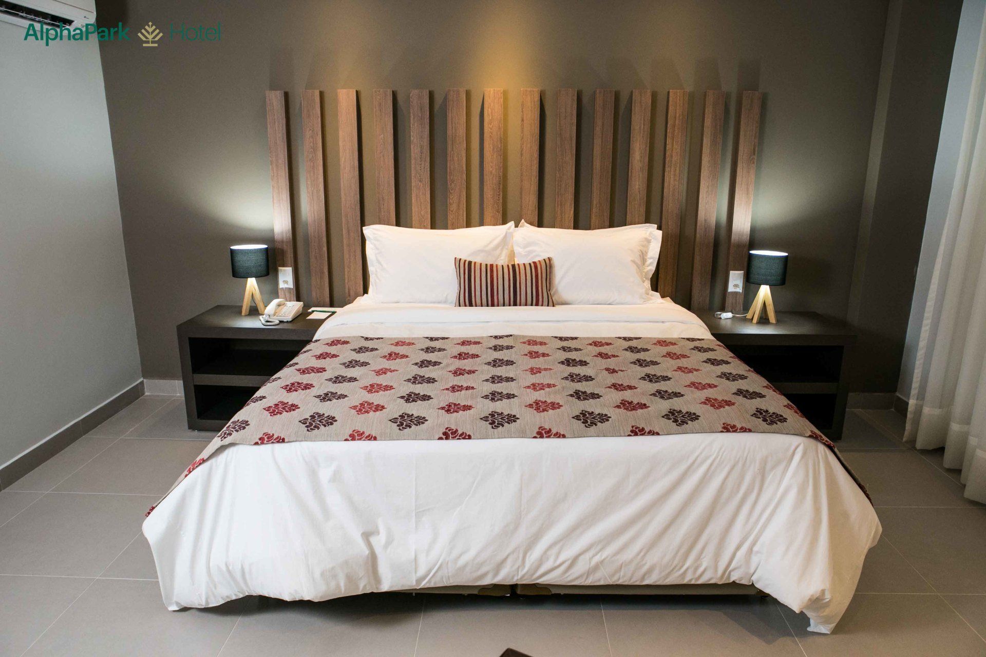 Um quarto de hotel com uma cama grande e uma cabeceira de madeira
