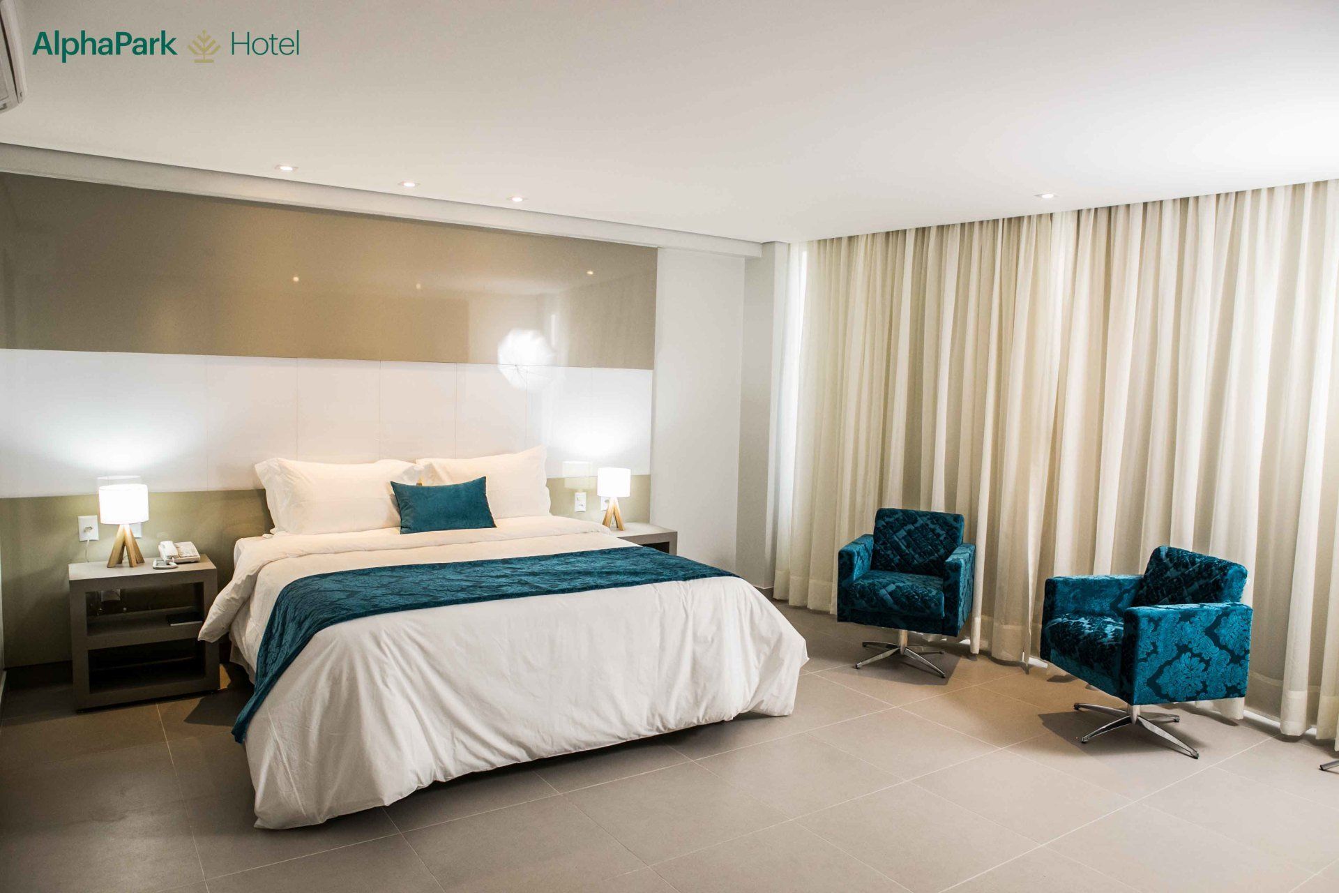 Um quarto de hotel com uma cama king size e duas cadeiras.