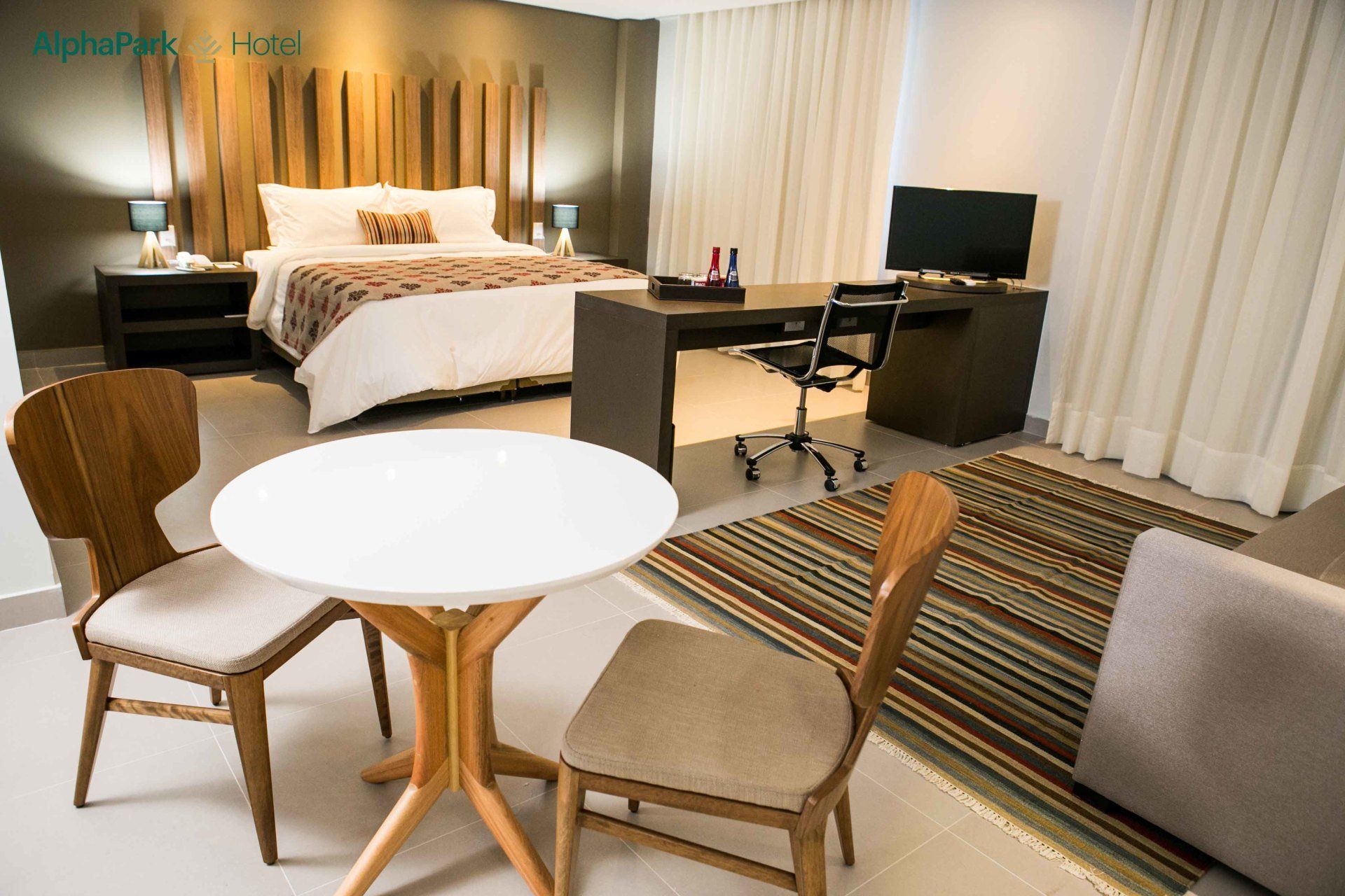 Um quarto de hotel com uma mesa e cadeiras em frente à cama.