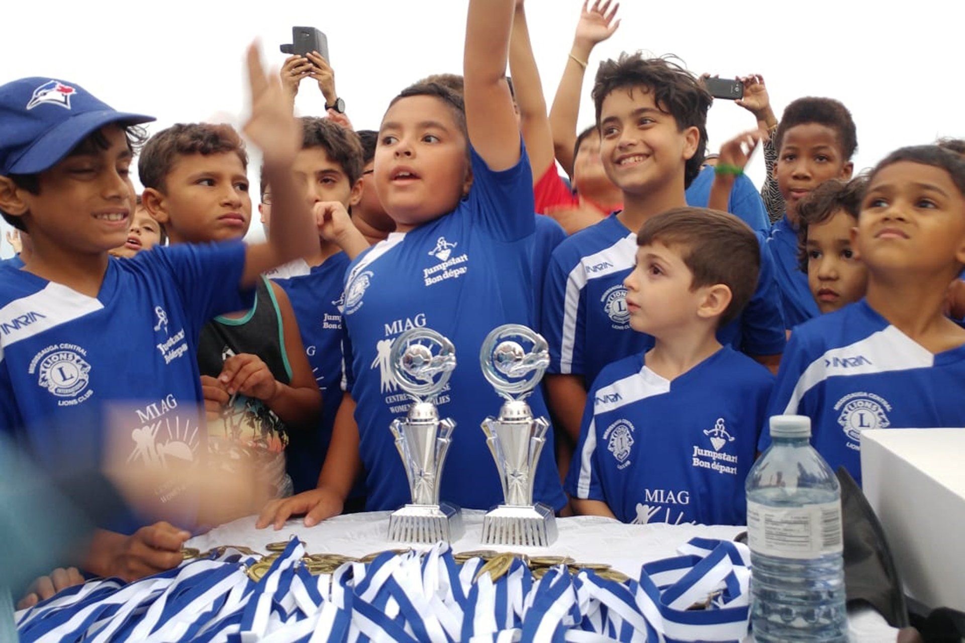 A group of young boys are standing around a table with trophies.