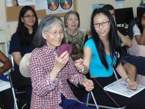 A group of people are sitting in chairs and one woman is knitting