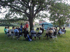 A group of people are sitting in a circle under a tree