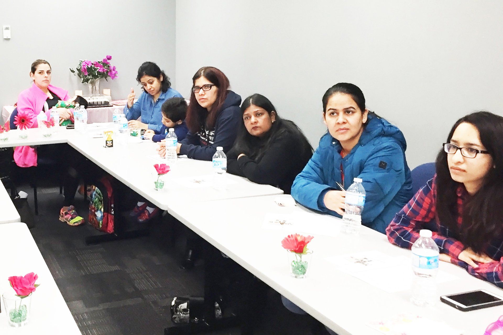 A group of women are sitting at a long table in a room.