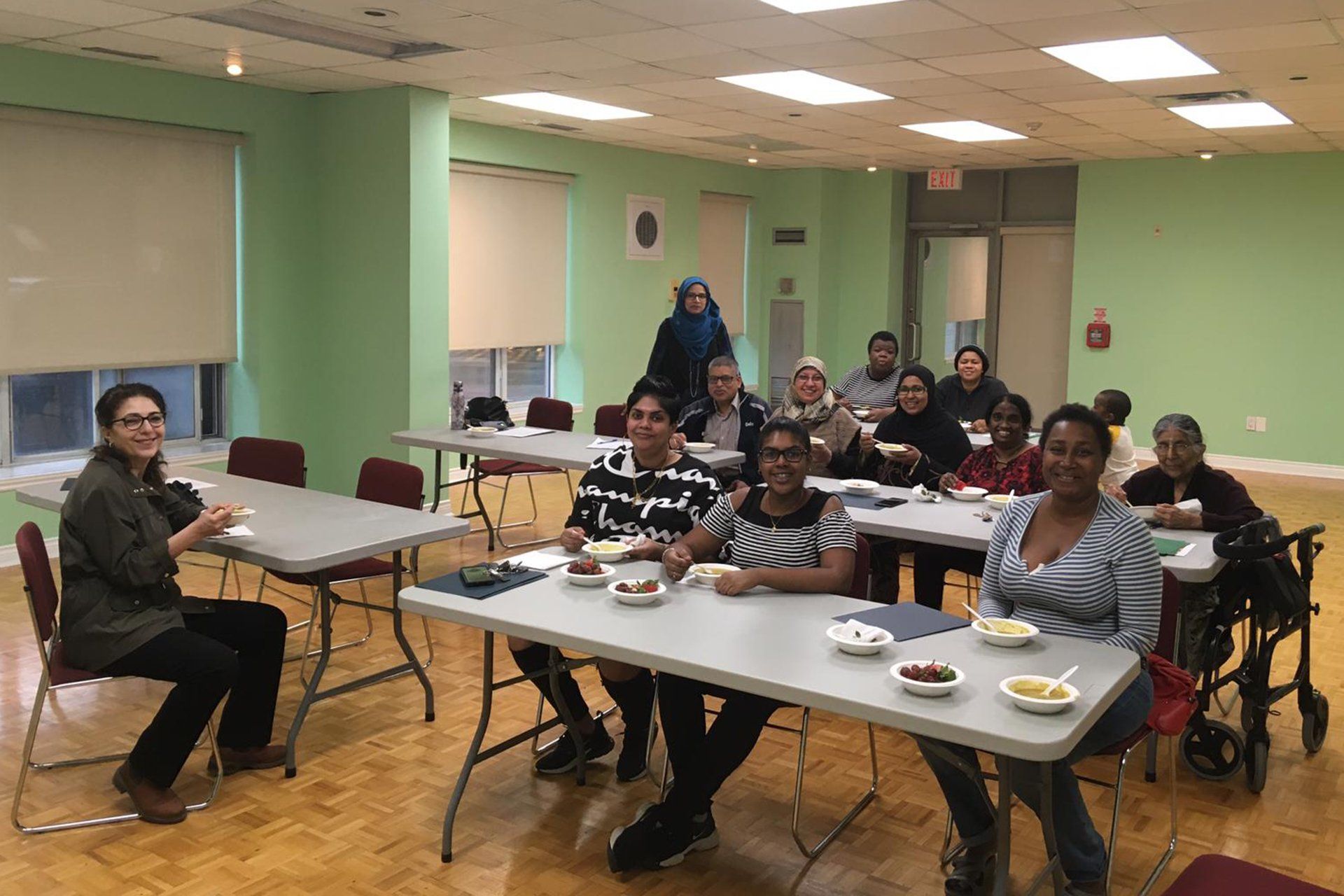 A group of people are sitting at tables in a room eating food.