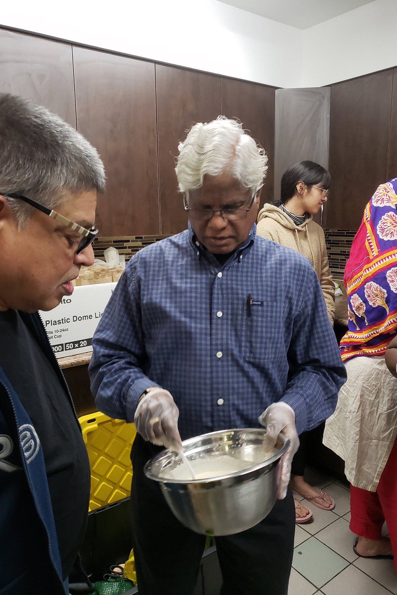 A man is holding a bowl of food in a kitchen.