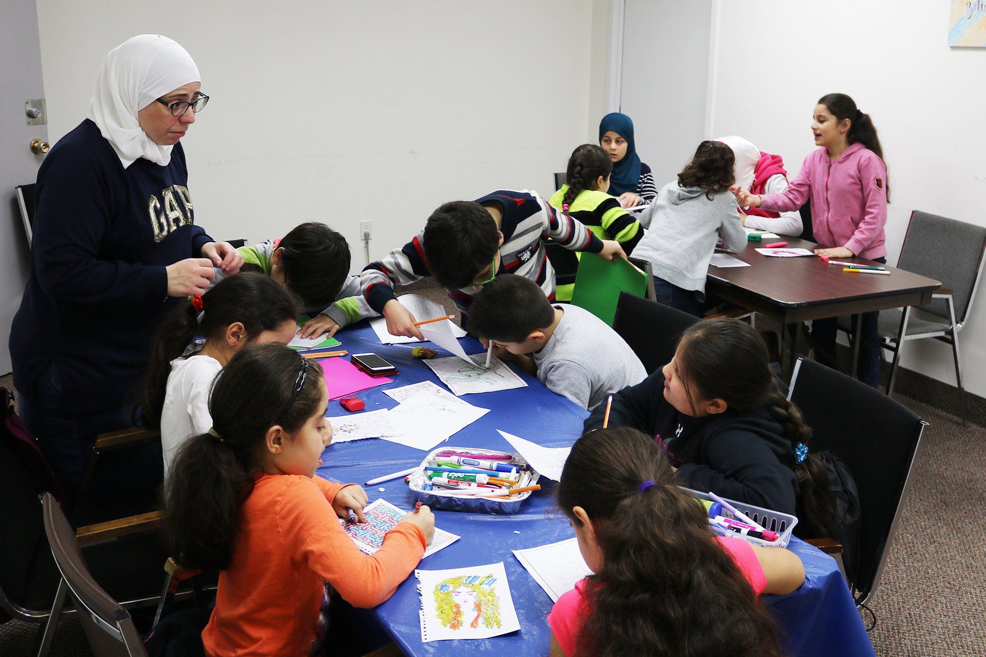 A group of children are sitting around a table in a room.