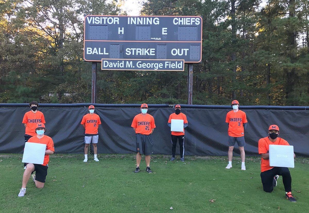 A group of people holding signs in front of a scoreboard that says ball strike out