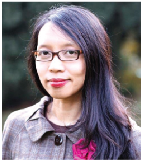 A woman wearing glasses and a coat is smiling for the camera.