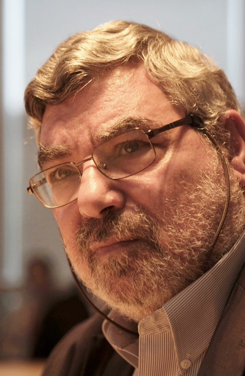 A man with a beard and glasses is looking at the camera.