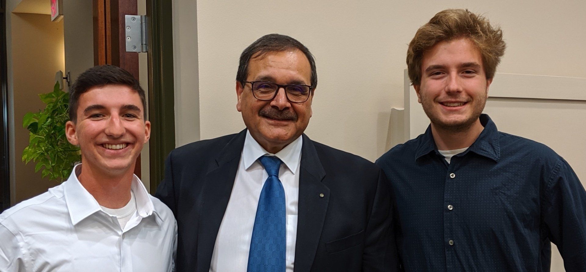 A man in a suit and tie is posing for a picture with two young men.