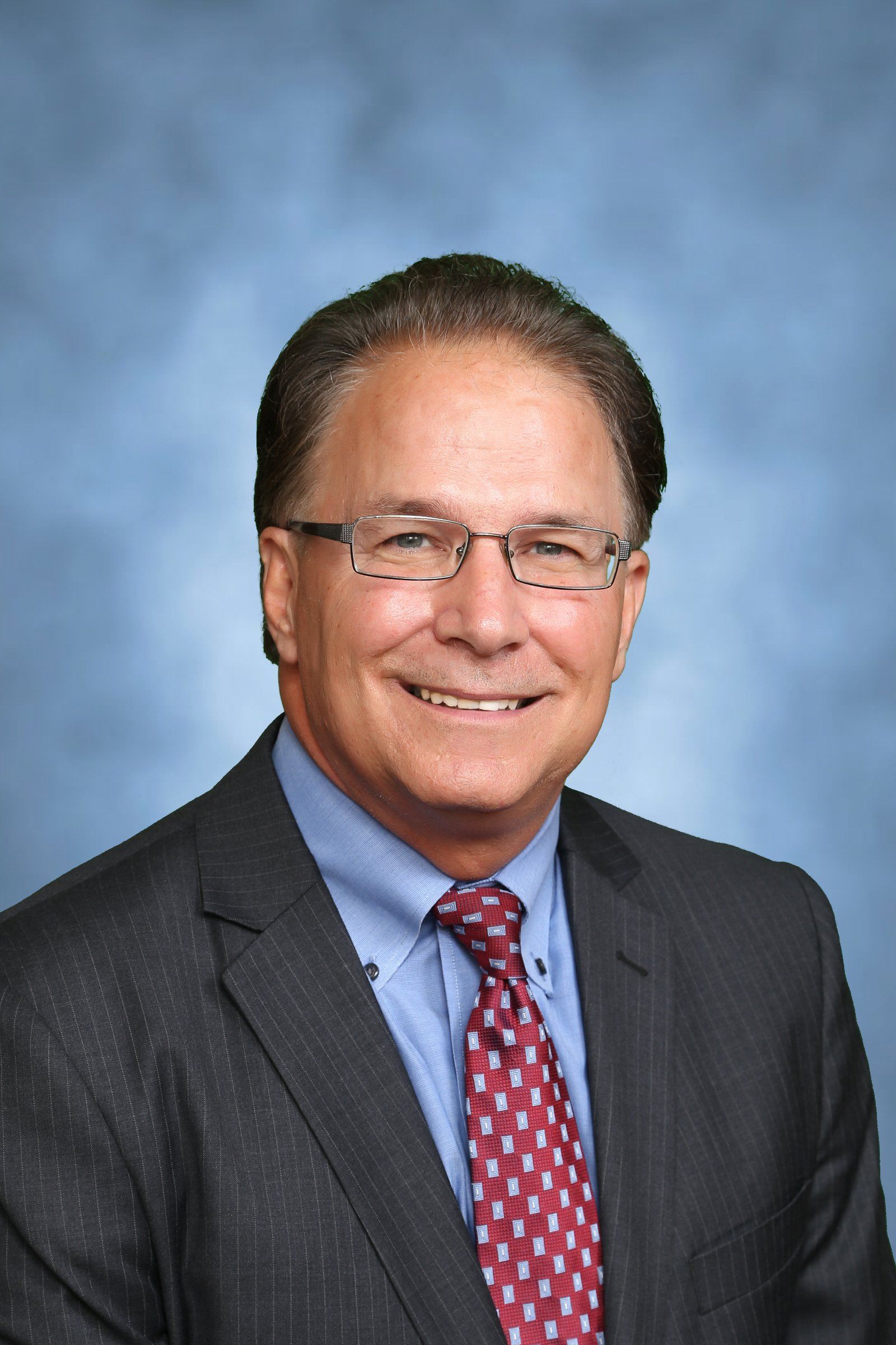 A man in a suit and tie is smiling for the camera.