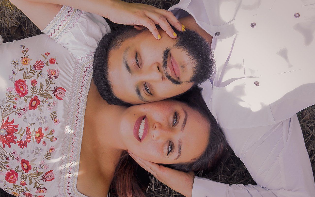 A man and a woman are laying on top of each other in the grass.
