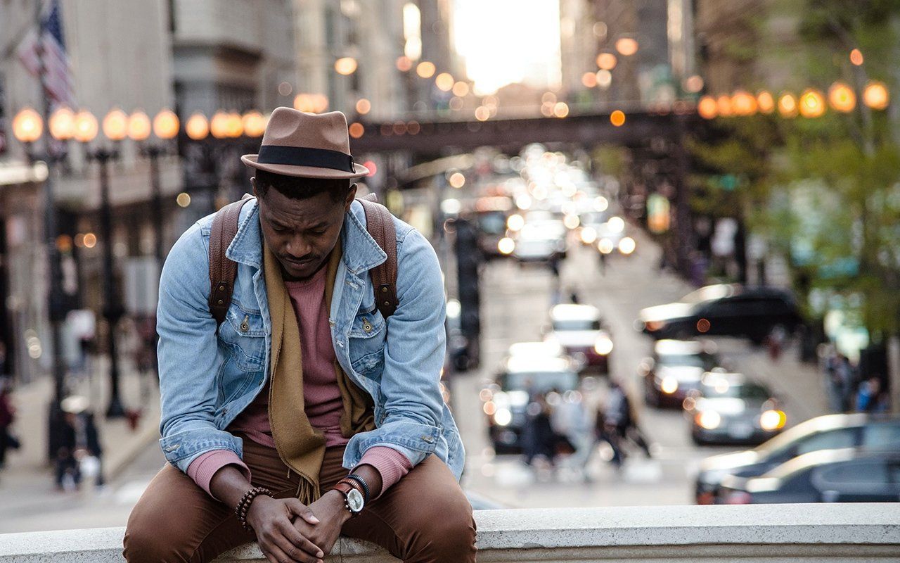 A man is sitting on a ledge overlooking a city street.