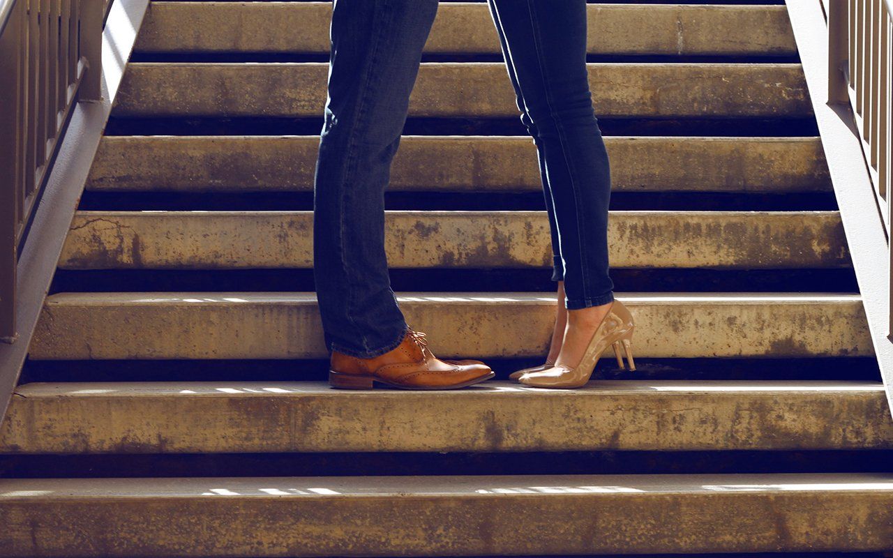 A man and a woman are kissing on the stairs.