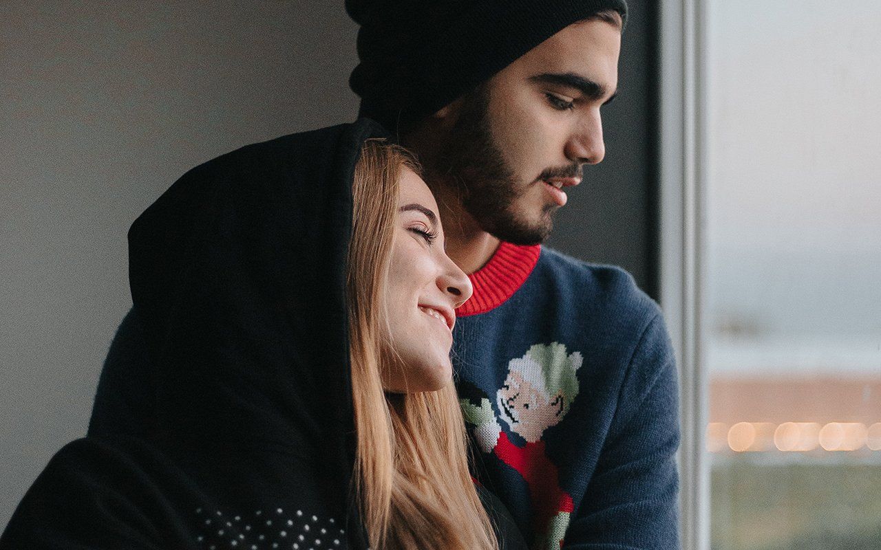 A man and a woman are looking out of a window.