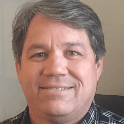 A man in a plaid shirt is smiling for the camera