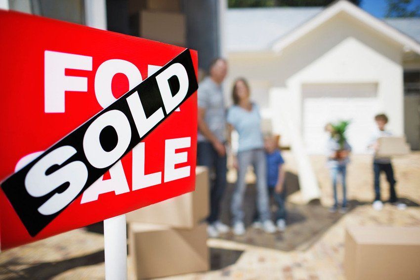 Sold sign on house with family in the background.