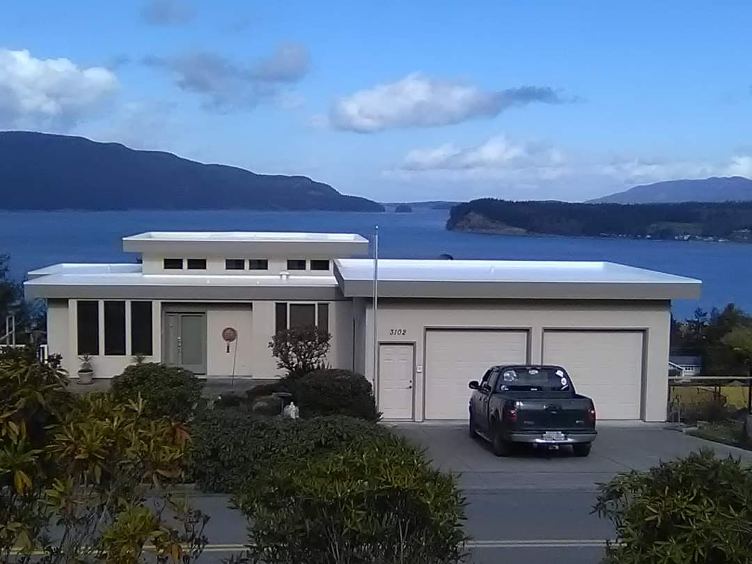 A truck is parked in front of a house overlooking a body of water