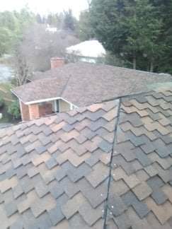 A roof with a lot of tiles on it and a house in the background.