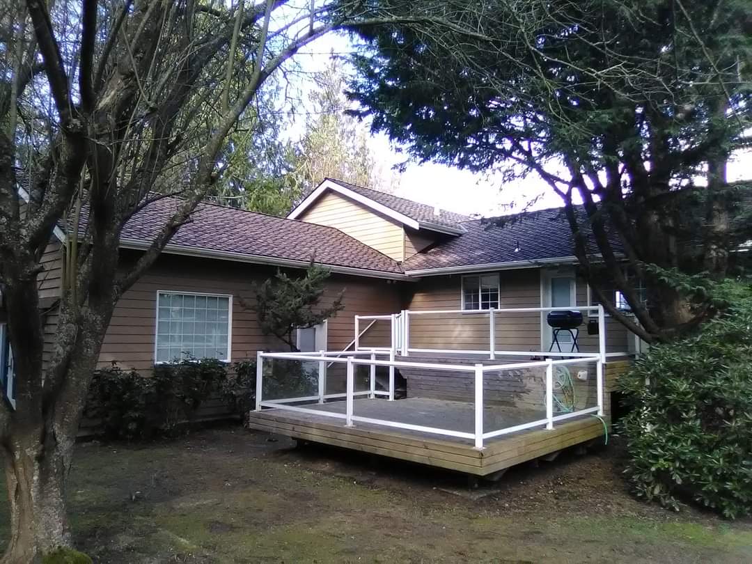 A house with a large deck in front of it surrounded by trees.