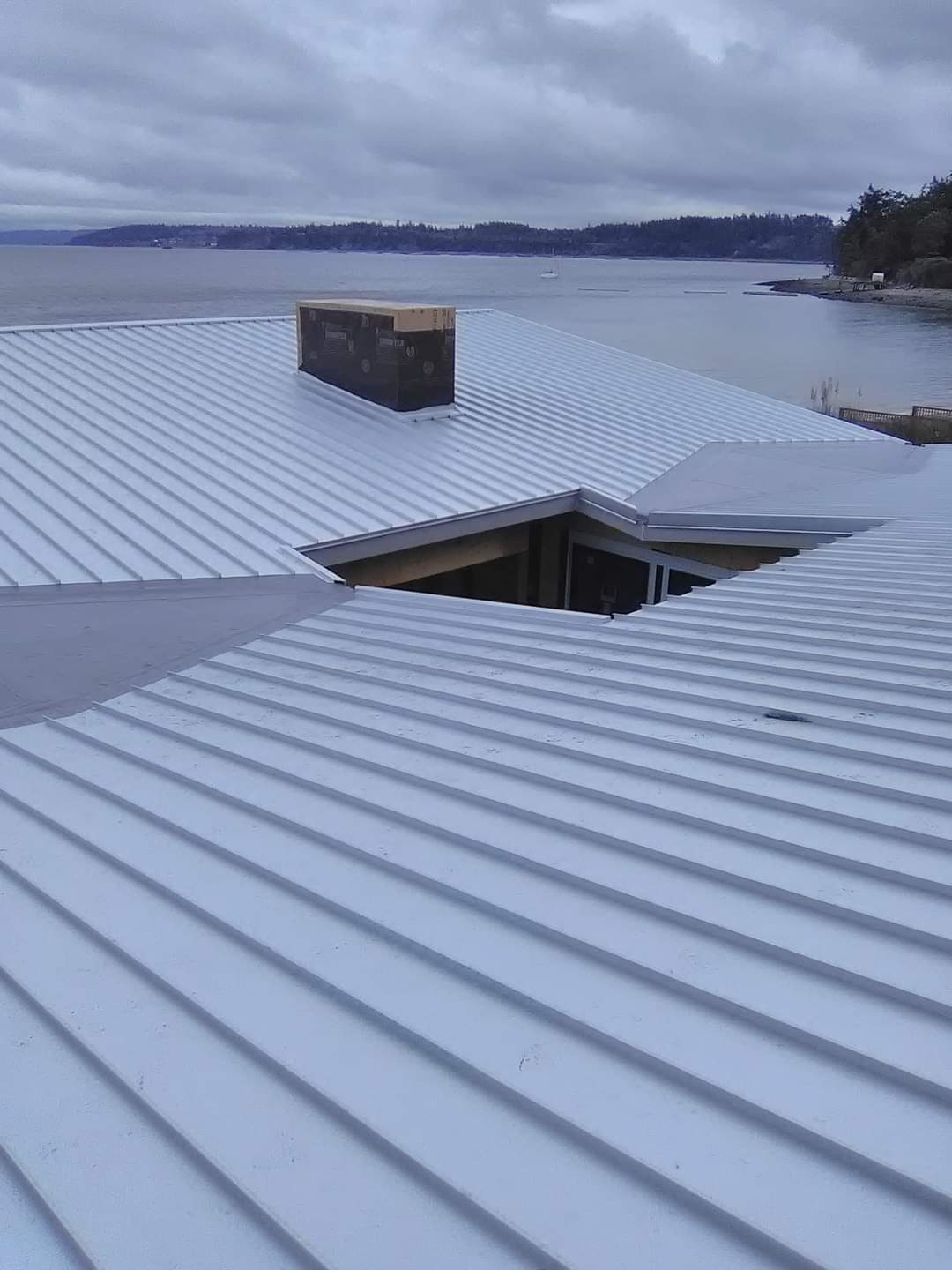 A white roof with a chimney on it overlooking a body of water