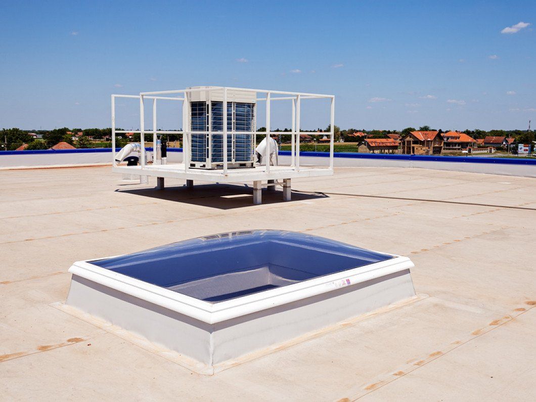A roof with a skylight and a building in the background