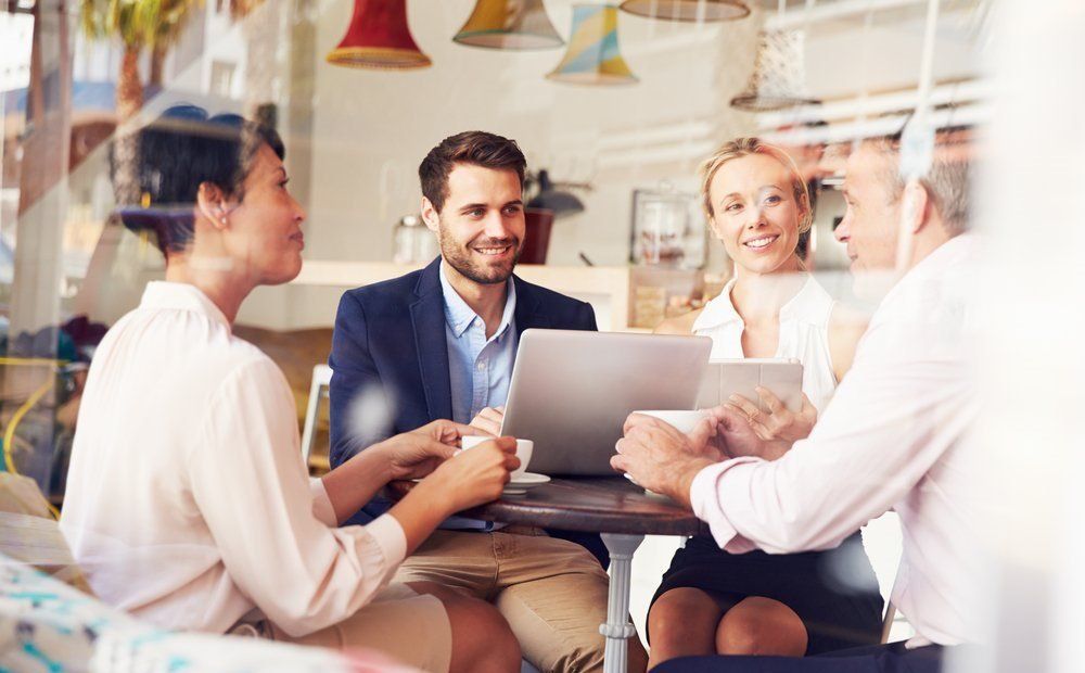A group of people are sitting around a table with laptops.
