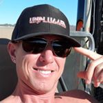 A man wearing a hat and sunglasses is sitting in a chair.