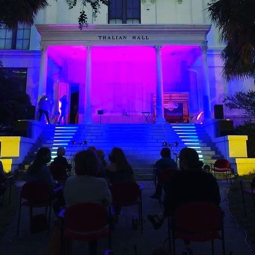 Outdoor concert at Thailand Hall, with purple-lit stage and seated audience in the foreground