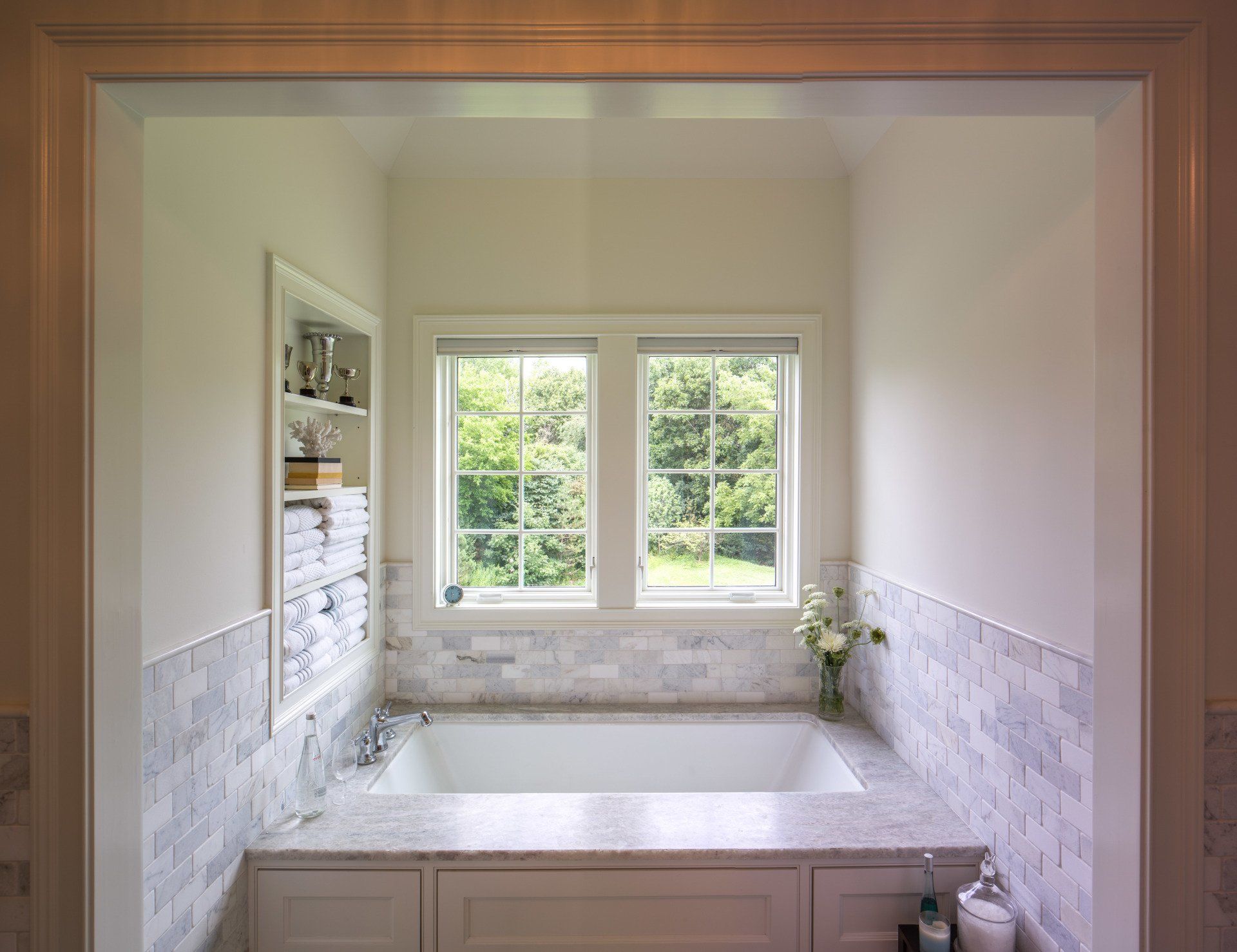 A bathroom with a tub and two windows.