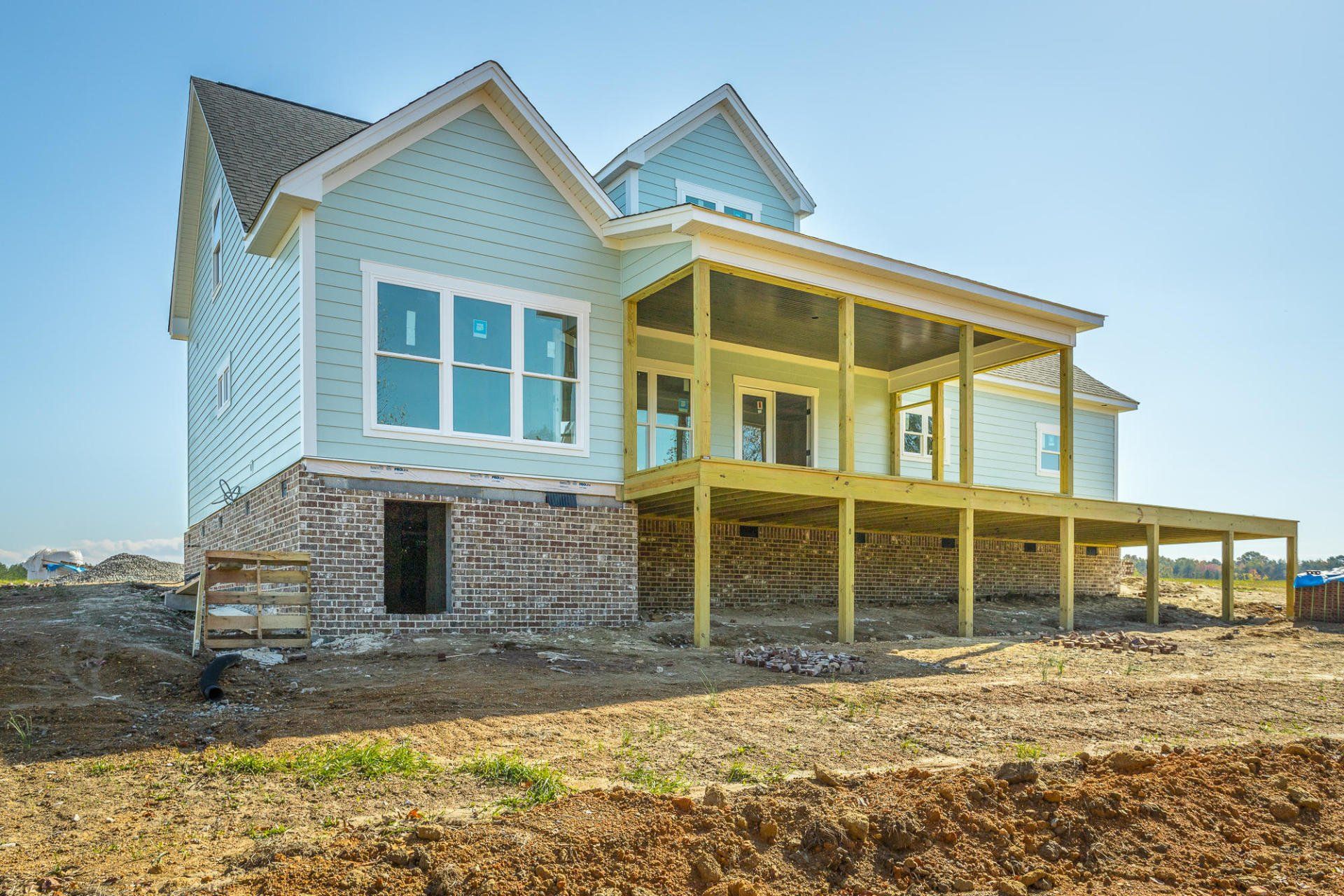 a large house is being built in a dirt field .