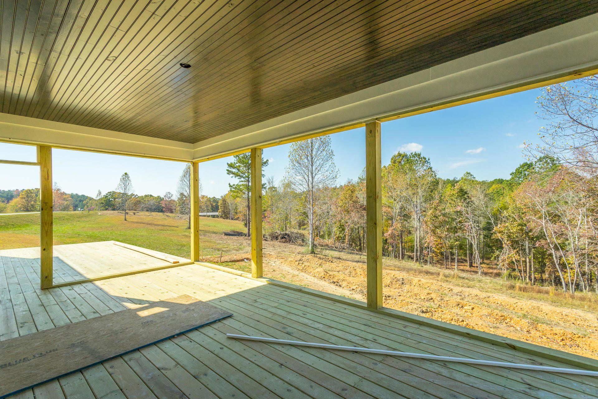 an empty deck with a view of a field and trees .