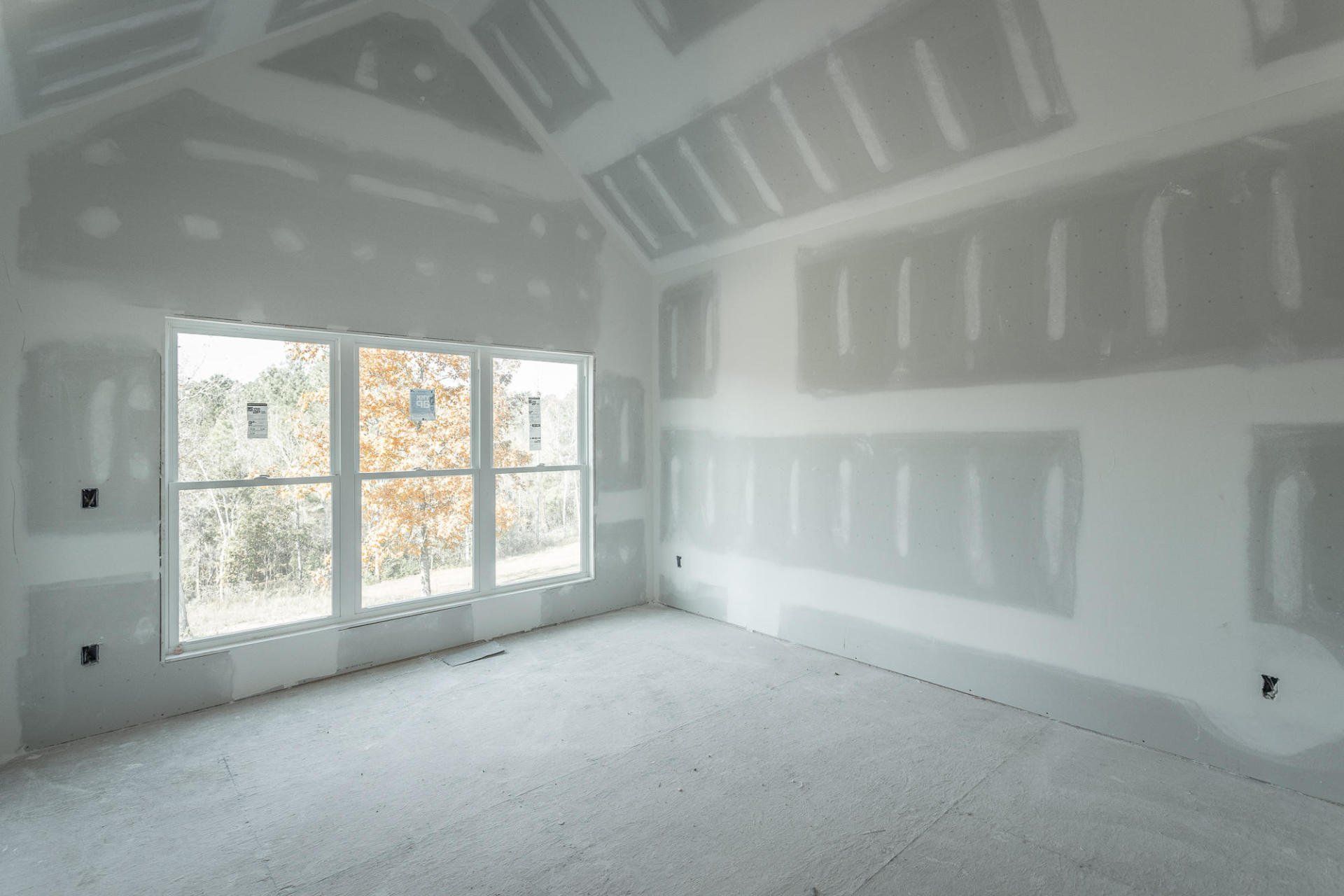an empty room with a lot of windows and drywall on the walls .