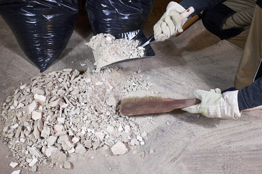 A cleaner collecting the dirt, sand and rocks from the after builders work during a builders cleaning job at Berkshire cleaning