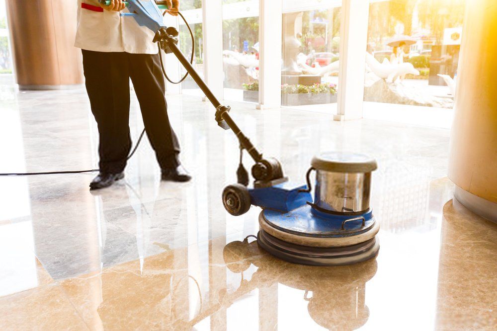 A cleaner using a floor cleaning machine to wipe the floor during a commercial cleaning  job
