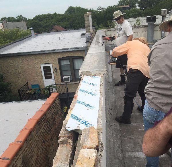 Crew removing capstones from parapet wall