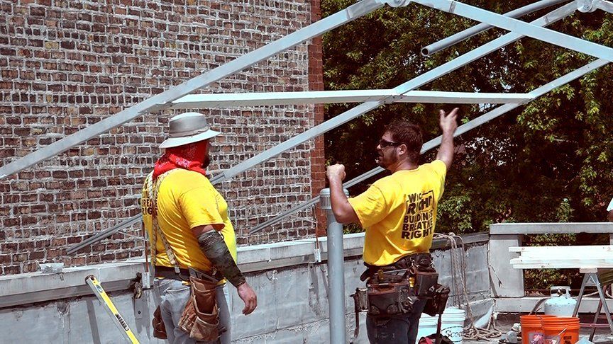 Two workers assembling a metal frame for construction tent