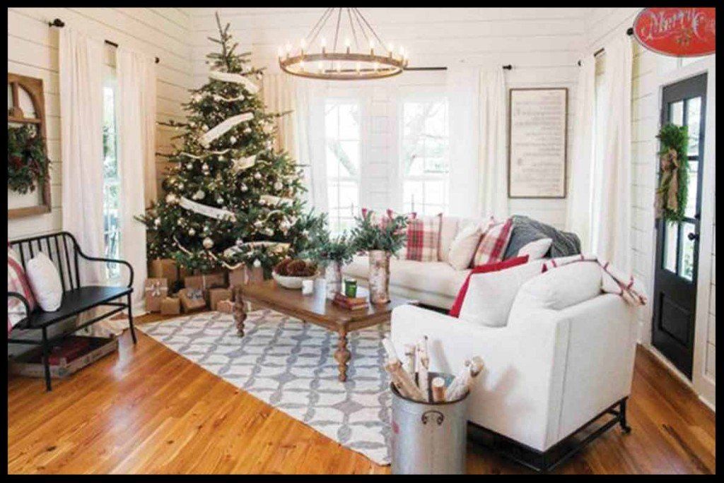 Cozy living room decorated for Christmas, with a tree, gifts, white couch, and wood floors.