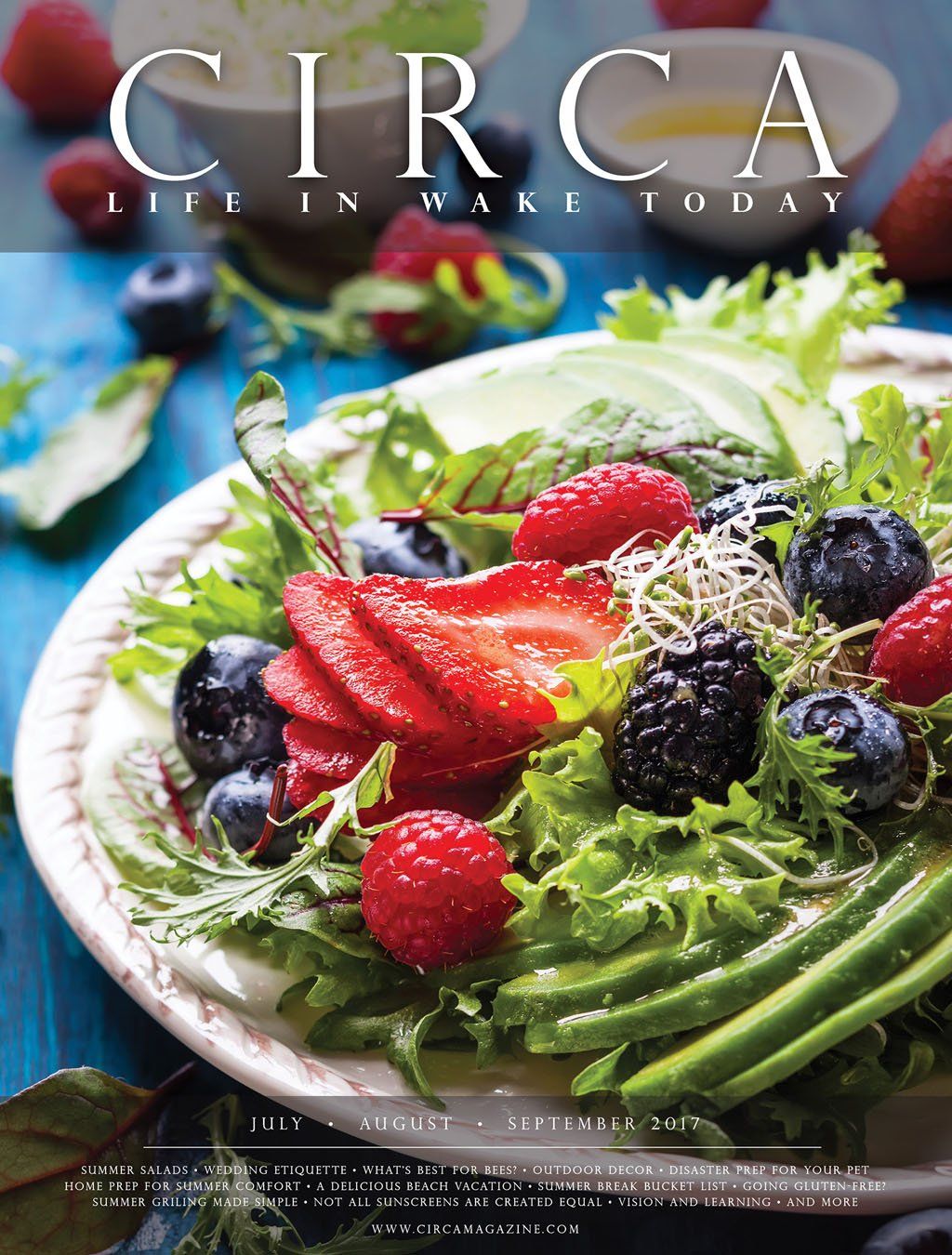 Magazine cover of a colorful salad with berries, avocado, and sprouts, on a white plate. 