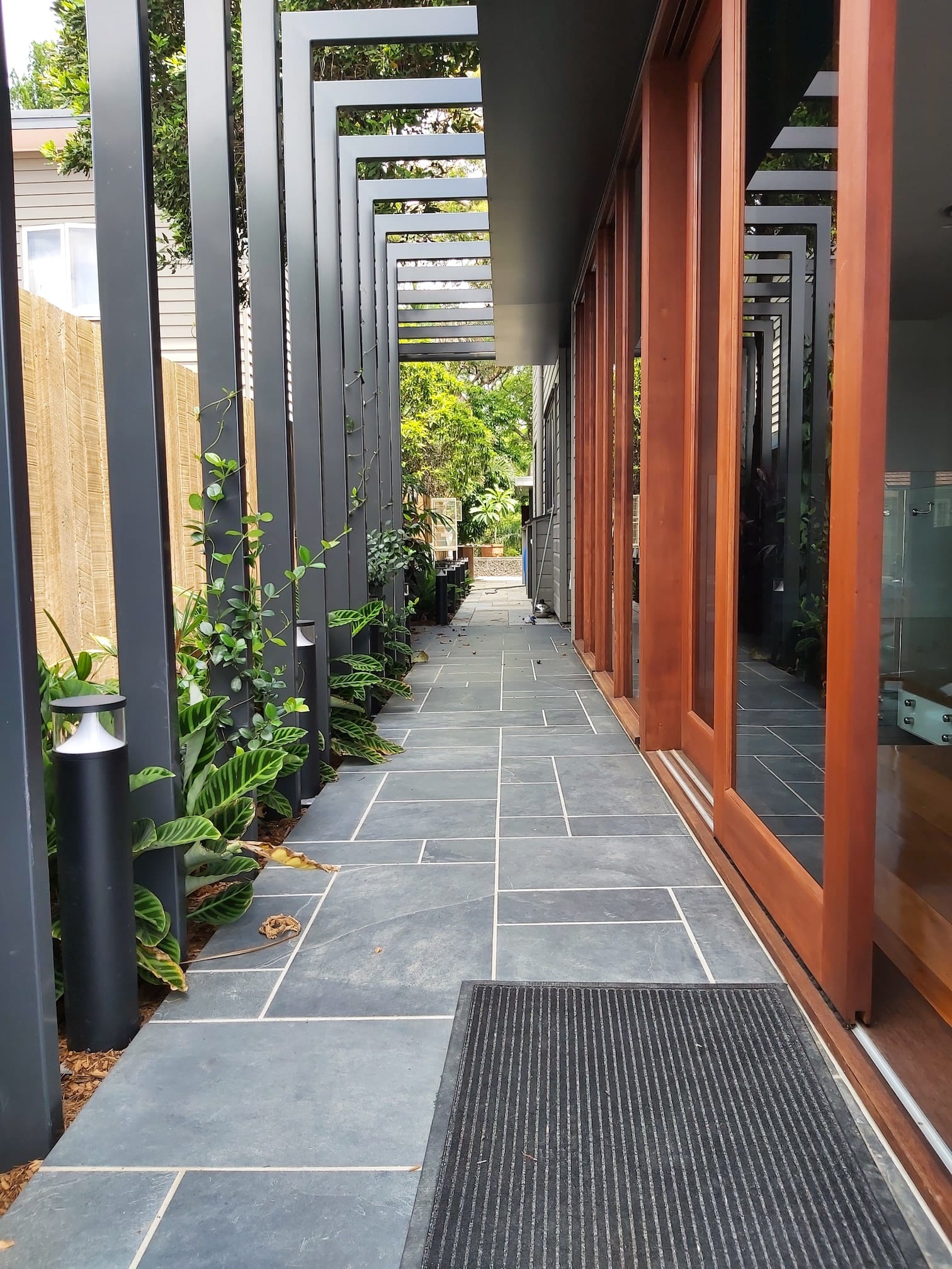 A long hallway with a pergola and sliding glass doors