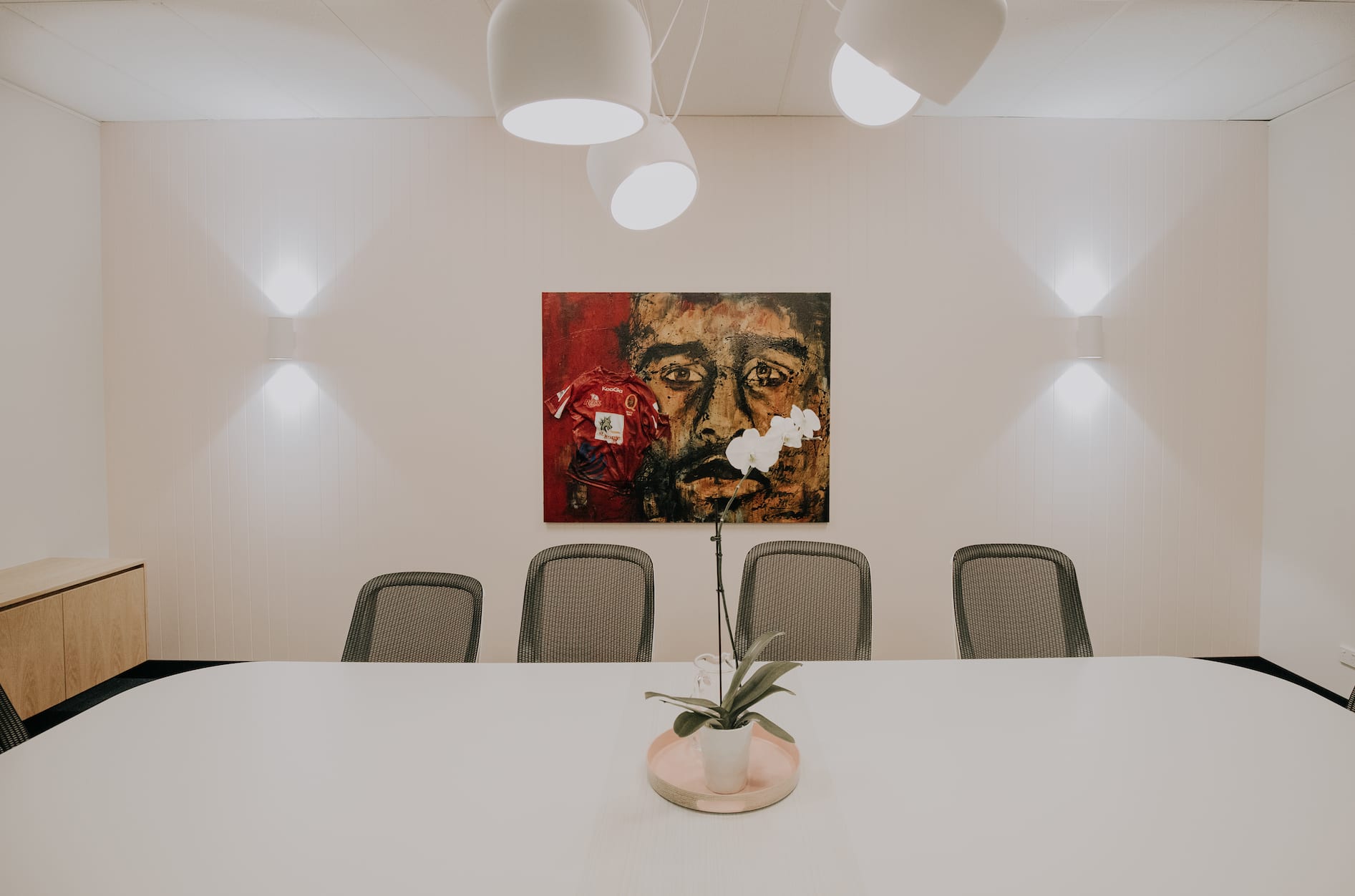 A conference room with a table and chairs and a painting on the wall.