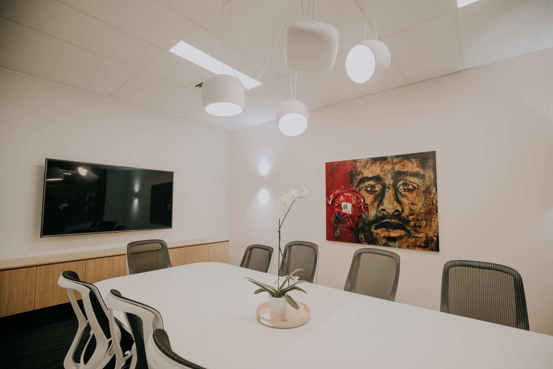 A conference room with a long table and chairs and a painting on the wall.