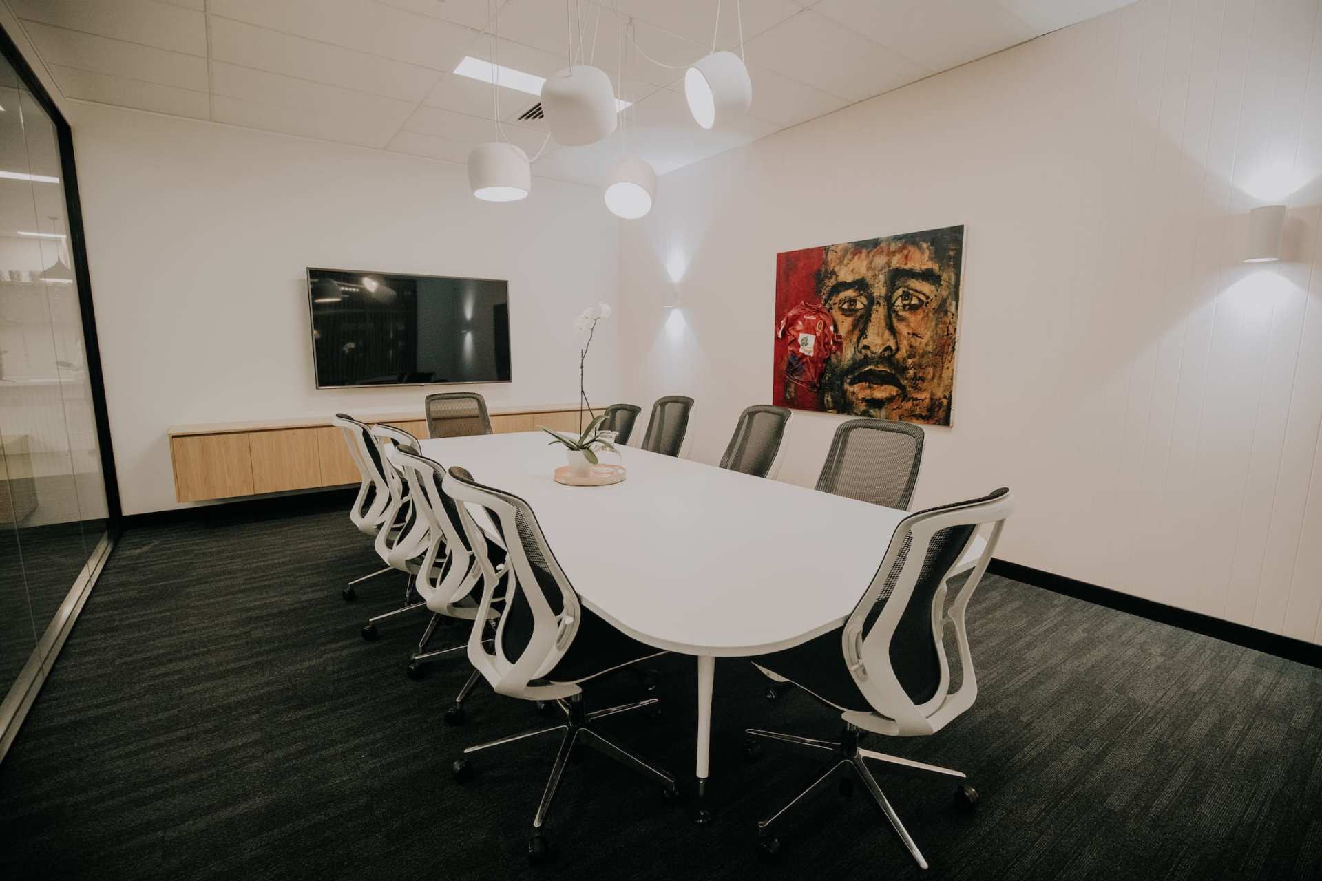 A conference room with a long table and chairs and a painting on the wall.