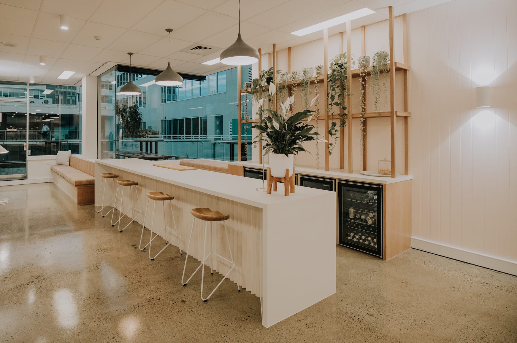 A kitchen with a long counter and stools and a refrigerator.