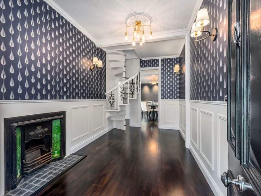 A hallway with a fireplace and stairs in the background