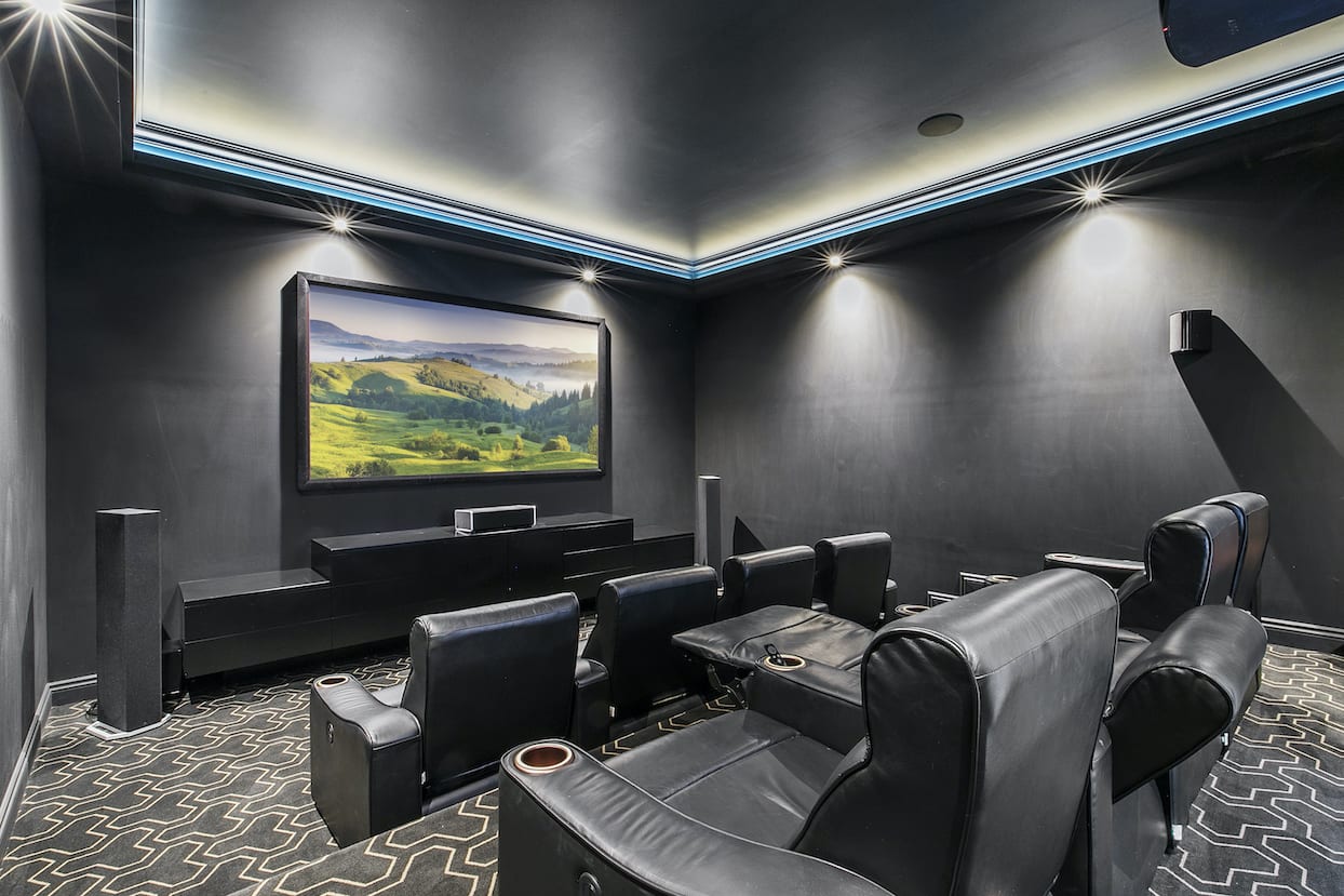 A home theater with a large flat screen tv on the wall.