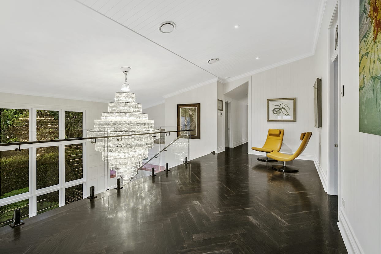 A hallway with a chandelier hanging from the ceiling and a yellow chair.