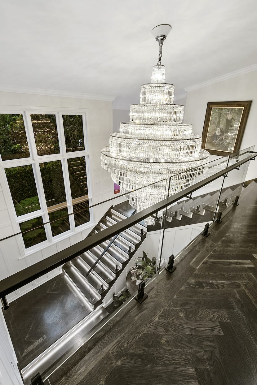 There is a large chandelier hanging from the ceiling above the stairs.